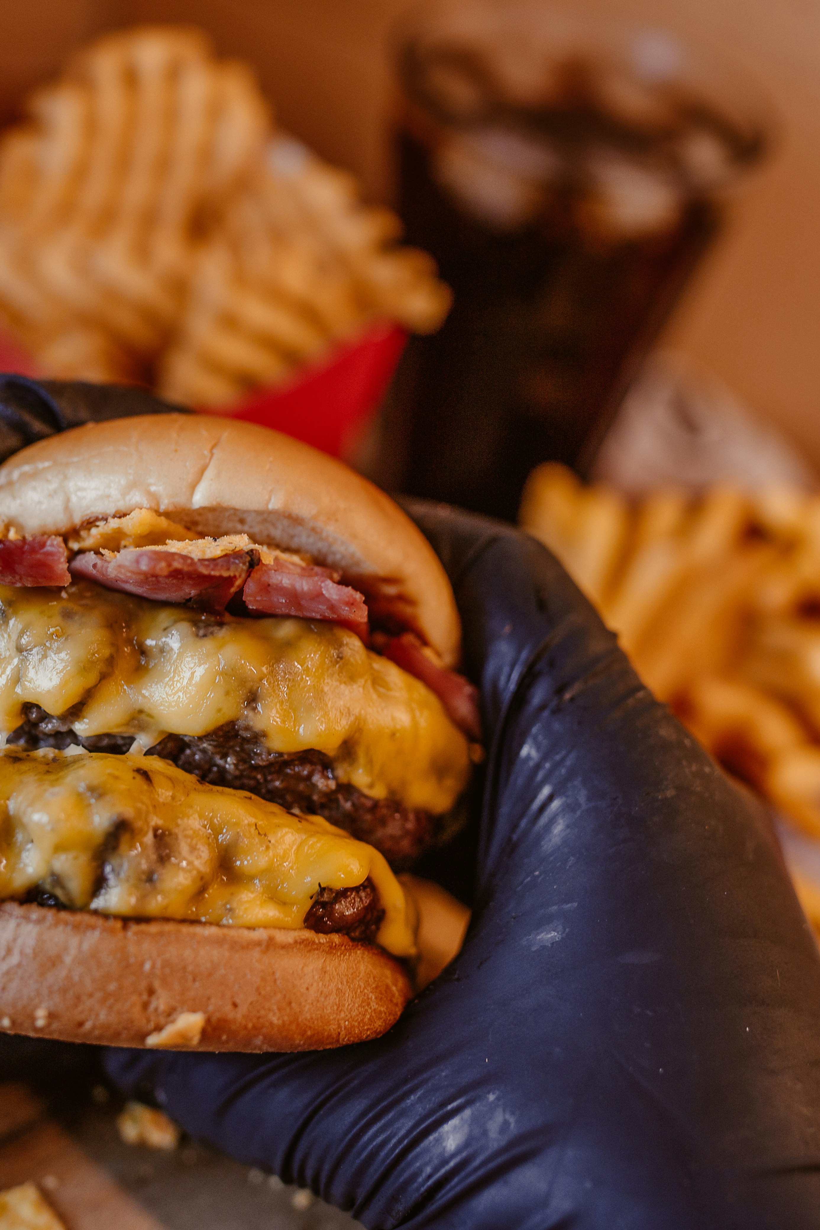 person holding burger with patty and cheese